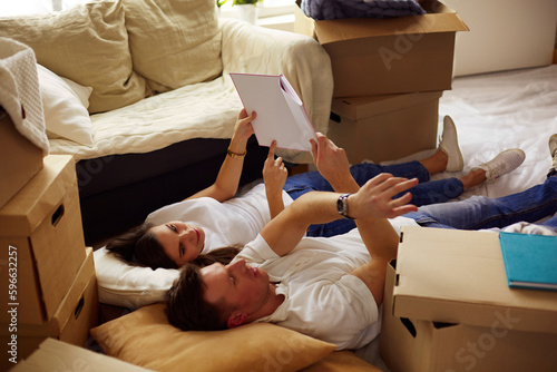 Young couple lying on the floor after unpacking boxes in their new house.