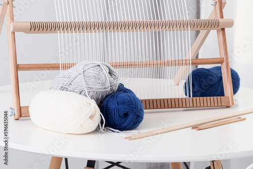 Tools for weaving tapestries. Wooden weaving frame and yarn on a table on a white background. Warp thread stretched over a weaving frame. The ancient art of weaving cloth.