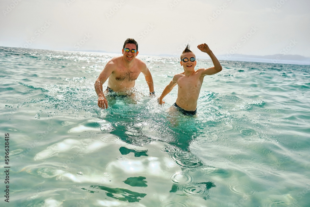 Happy family in swimming goggles, father and son bonding, play, swim in the sea looking at view enjoying summer vacation. Togetherness Friendly concept Happy family in swimming goggles, father and son bonding, play, swim in the sea looking at view enjoying summer vacation. Togetherness Friendly concept