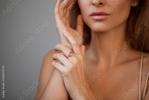 cropped view of young woman with natural lips in ring isolated on grey