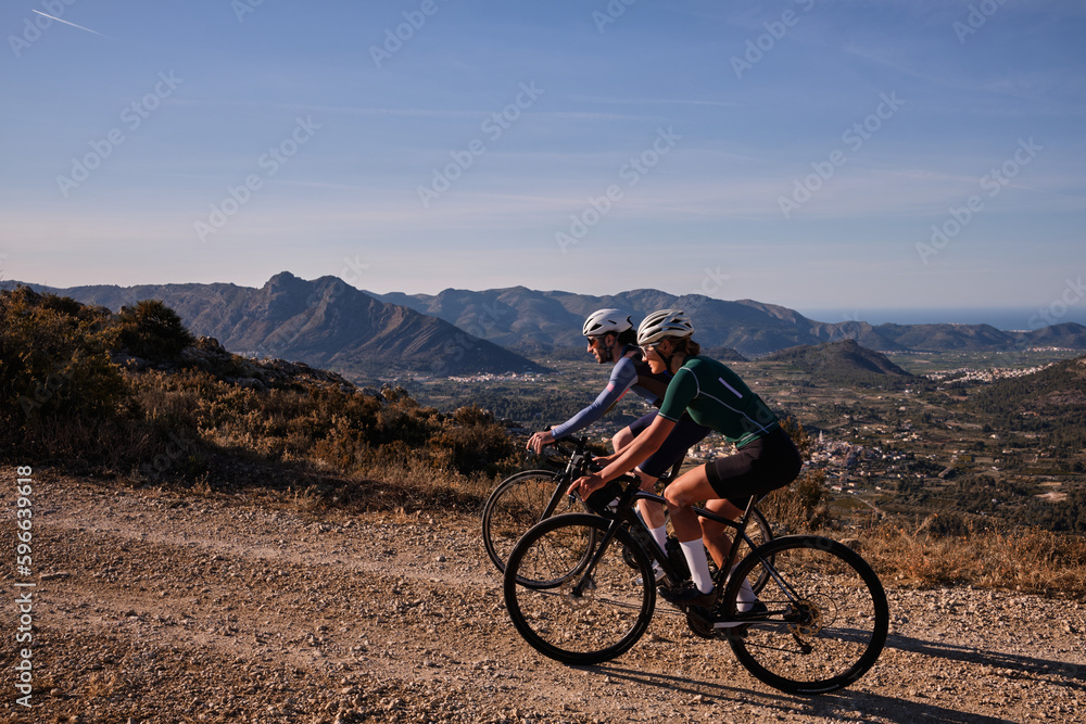 Two cyclists are riding along a scenic mountain gravel route.Cyclists are practicing on gravel road.Beautiful sunny day for cycling.Spain.