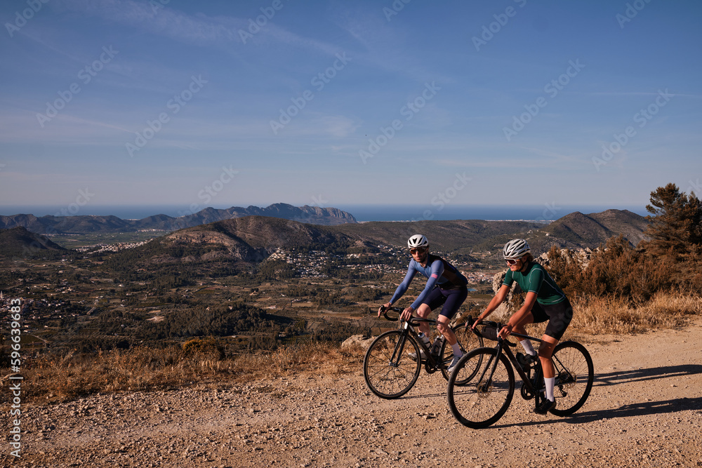 Gravel adventure.Two cyclists are riding along a scenic mountain gravel route.Cyclists are practicing on gravel road.Beautiful sunny day for cycling.Spain. Gravel adventure.Two cyclists are riding along a scenic mountain gravel route.Cyclists are practicing on gravel road.Beautiful sunny day for cycling.Spain.