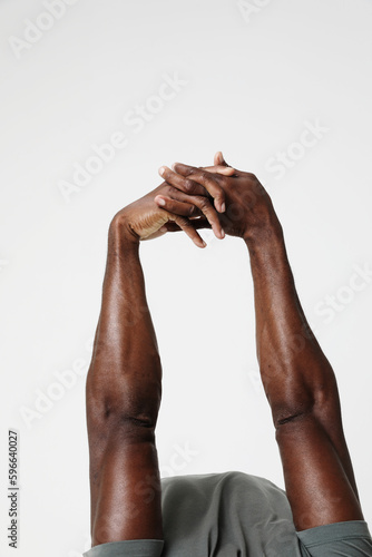 Cropped photo of athletic black man doing muscle stretching exercises. Vertical.