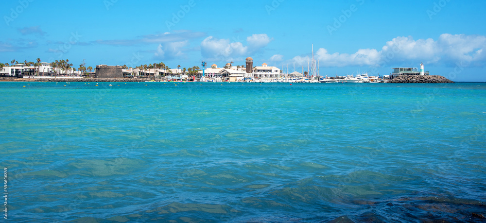 Impresionante mar turquesa en calma en la costa de Caleta de Fuste en la turística Fuerteventura durante un día soleado con un cielo azul claro en las Islas Canarias