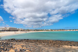 Vista panorámica de Caleta de Fuste frente a una impresionante playa de arena blanca llena de turistas y el mar cristalino durante un día soleado en la turística Fuerteventura en las Islas Canarias.