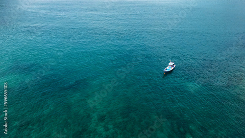 Into the blue. Boat sailing alongside the coastline of Phuket. © Yannick