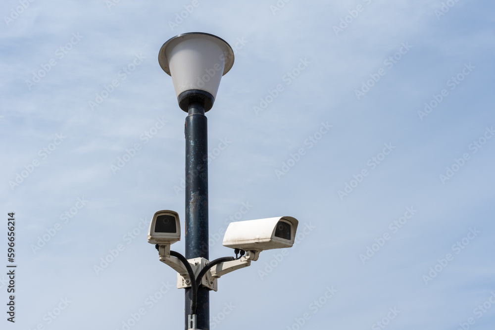 Surveillance cameras mounted on a lamp post against a blue sky. security cctv camera. Security in the city. Surveillance cameras mounted on a lamp post against a blue sky. security cctv camera. Security in the city.