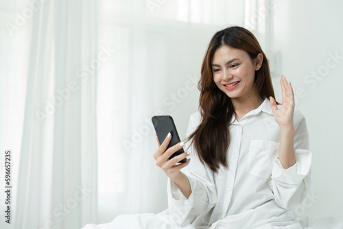Young woman video calls with family or friends in bedroom