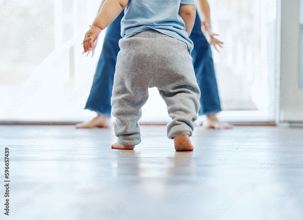 Taking his first steps on his own. Cropped shot of an unrecognizable little boy learning to walk with the help of his mother at home. Taking his first steps on his own. Cropped shot of an unrecognizable little boy learning to walk with the help of his mother at home.