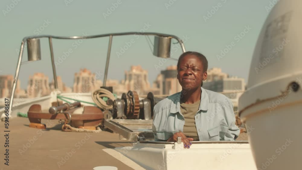 Slowmo portrait of young African American woman getting on boat deck climbing up from hatch, smiling at camera squinting from sun Slowmo portrait of young African American woman getting on boat deck climbing up from hatch, smiling at camera squinting from sun