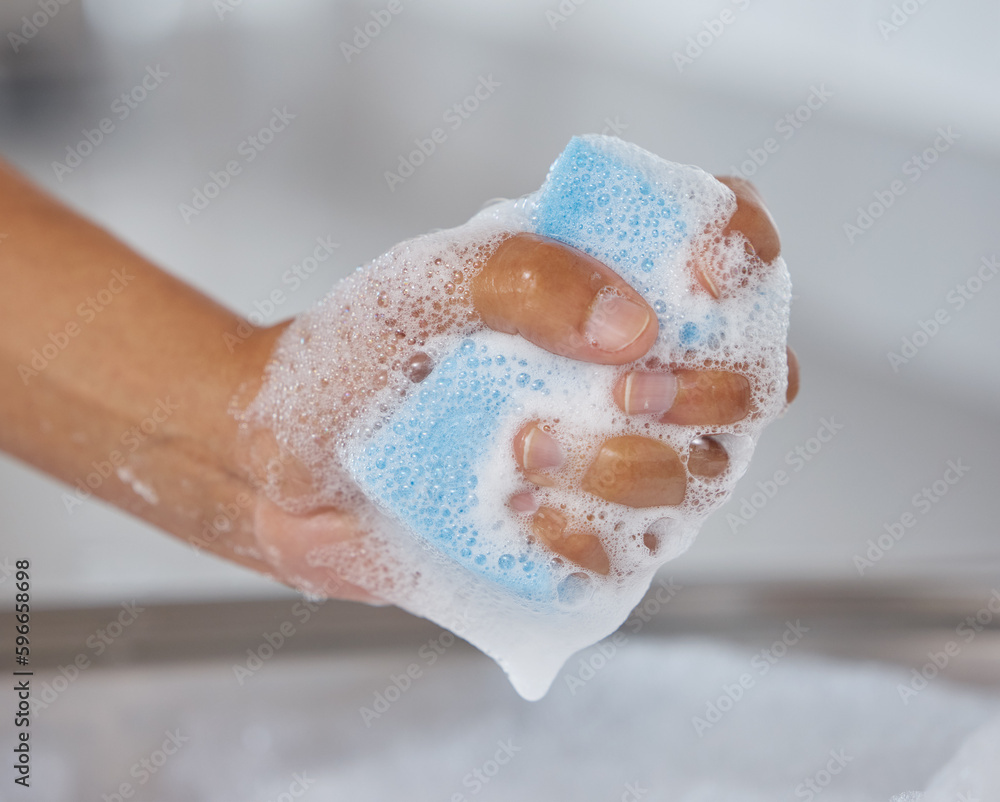 Fototapeta premium Time to tackle the dirty dishes. Closeup shot of an unrecognisable woman squeezing soap from a sponge at home.