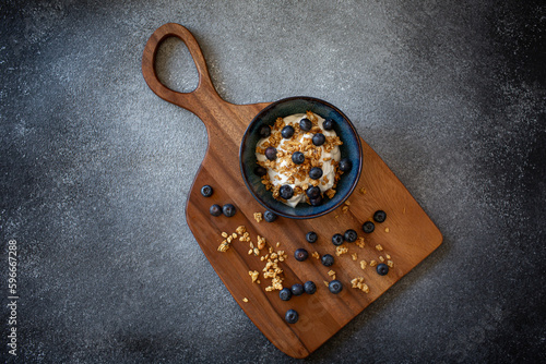 Bowl with greek yoghurt, granola and berries on dark grey background
