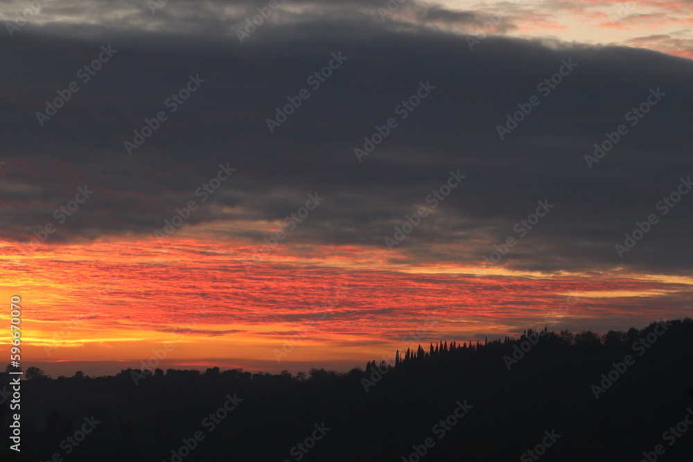 tramonto su una collina con nuvole rosse