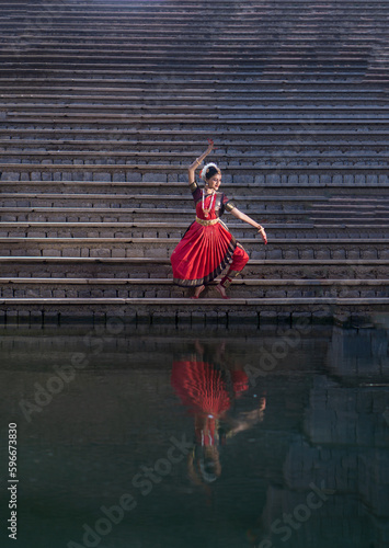 Indian Bharatanatyam dancer performing various steps wearing red saree. photo