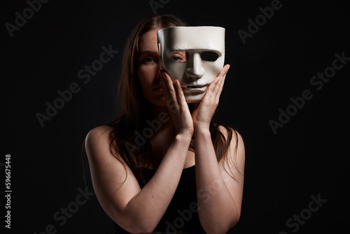 Its the only way Ill fit in. Studio shot of a woman hiding behind a blank mask.