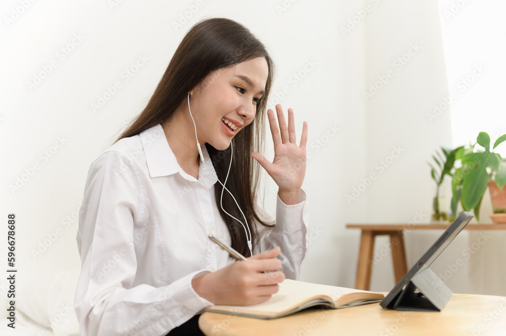 Portrait photo of Asian woman using video call communicate with business colleague friend or apply new job interview from home. Asian woman waving hand looking at camera. Portrait photo of Asian woman using video call communicate with business colleague friend or apply new job interview from home. Asian woman waving hand looking at camera.