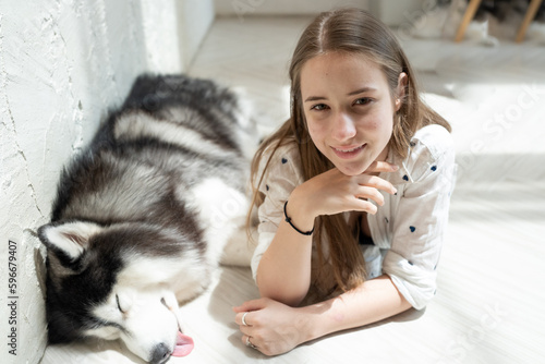 Young woman and her dog carefree at home background. Beautiful girl have fun playing with her adorable pet friend at leisure. Friendly malamute happy cuddle and sleep with owner who love and care.
