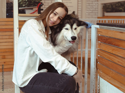 Young woman and her dog carefree at home background. Beautiful girl have fun playing with her adorable pet friend at leisure. Friendly malamute happy cuddle and sleep with owner who love and care.