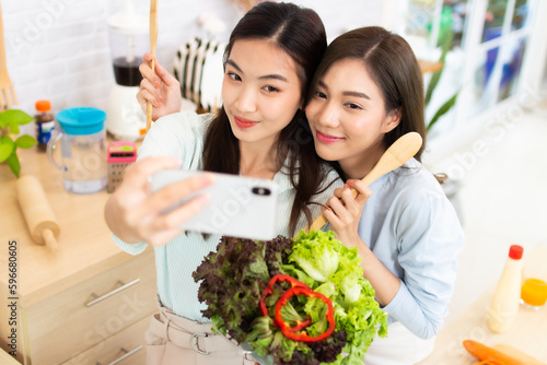 Two asian Young woman active woman taking a selfie in the kitchen. female having fun with healthy food salad.