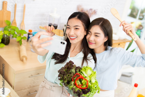 Two asian Young woman active woman taking a selfie in the kitchen. female having fun with healthy food salad.