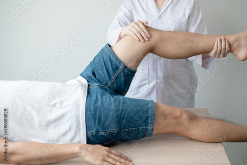 Therapist treating test the strength of the leg muscles of male patient.