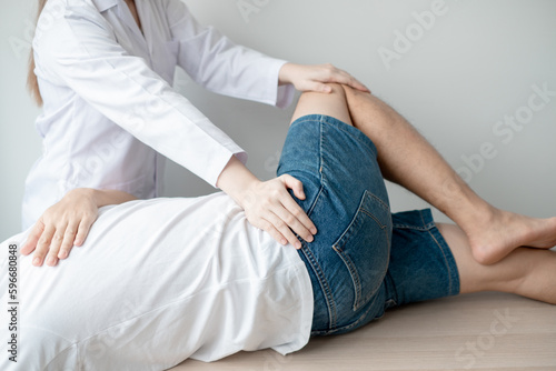 Therapist treating test the strength of the hip muscles of male patient.