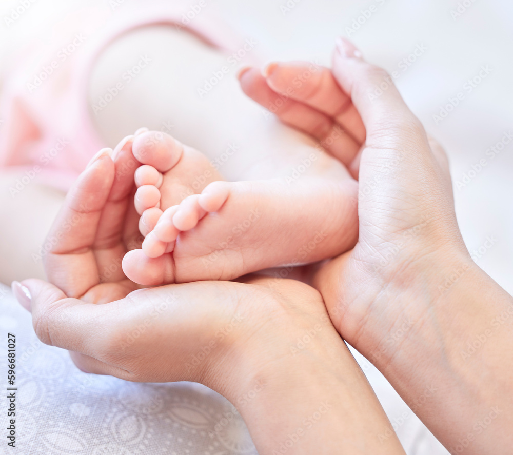 Mother holding baby feet. Closeup of tiny newborn baby feet held by a parent. Small baby toes. Little baby lying on a bed. Woman holding feet of little baby girl. Innocent infant being held by mother Mother holding baby feet. Closeup of tiny newborn baby feet held by a parent. Small baby toes. Little baby lying on a bed. Woman holding feet of little baby girl. Innocent infant being held by mother