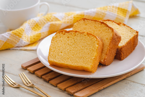 Butter cake sliced on white plate and cup of coffee