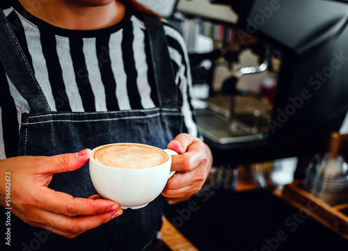 A cup of coffee cappuccino menu ready to serve in hand woman barista in the coffee shop
