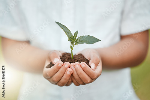 Giving back. Shot of an unrecognizable little boy holding plants growing out of soil.