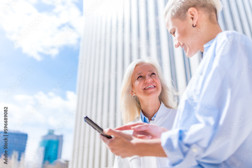 Executive women and businesswoman in a business area, empowered women smiling looking at a tablet, one morning laughing and having a great time Executive women and businesswoman in a business area, empowered women smiling looking at a tablet, one morning laughing and having a great time