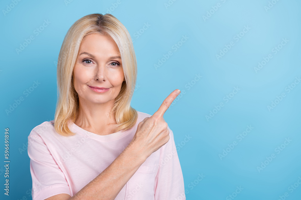 Photo of pretty aged person indicate finger empty space promo isolated on blue color background