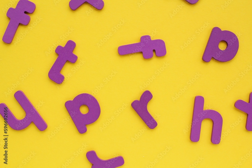 Purple alphabet letters on yellow background. World Dyslexia Day concept. Solving the educational problem of reading. Medical and mental health awareness. Logopedy, psychology, learning lessons Purple alphabet letters on yellow background. World Dyslexia Day concept. Solving the educational problem of reading. Medical and mental health awareness. Logopedy, psychology, learning lessons