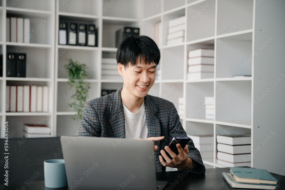 Portrait of young man sitting at his desk in the office Portrait of young man sitting at his desk in the office