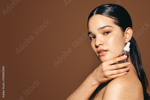 Using female cosmetic products for healthy skin: Portrait of a confident young woman holding face serum