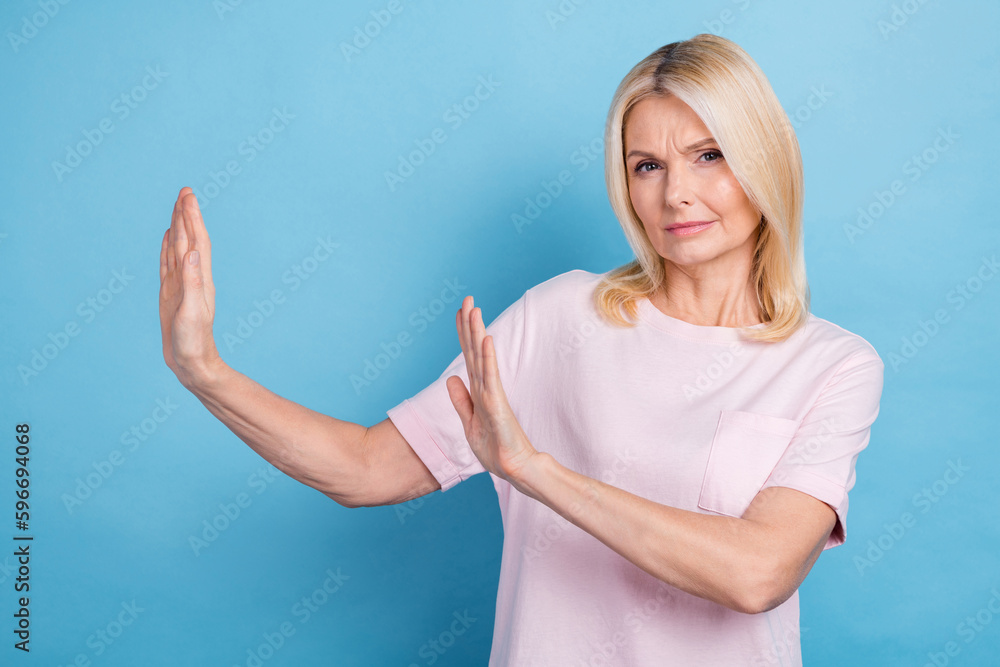 Photo of serious focused aged lady arms palms show block stop gesture empty space isolated on blue color background