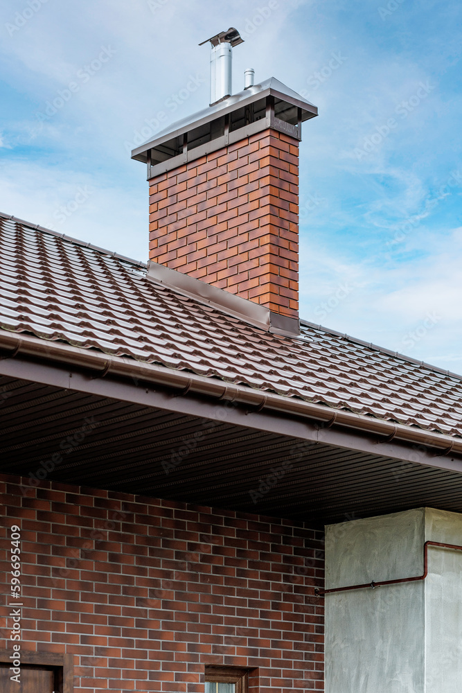 A chimney or ventilation pipe in a private house made of decorative bricks on the roof