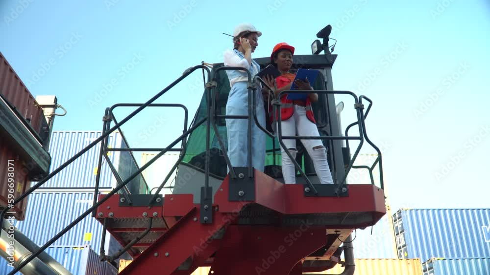 group of two diversity woman container worker working together with tablet computer on high of forklift in warehouse logistic in Cargo . cooperation of african american woman and Caucasian female. group of two diversity woman container worker working together with tablet computer on high of forklift in warehouse logistic in Cargo . cooperation of african american woman and Caucasian female.