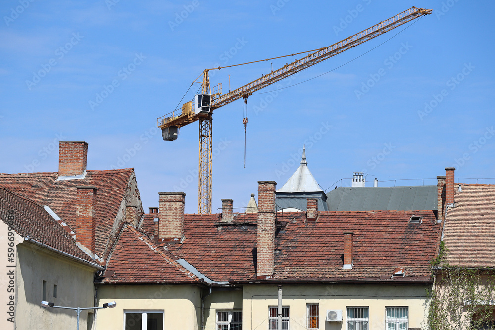 House roofs with smoke stacks and a tower crane in the background House roofs with smoke stacks and a tower crane in the background