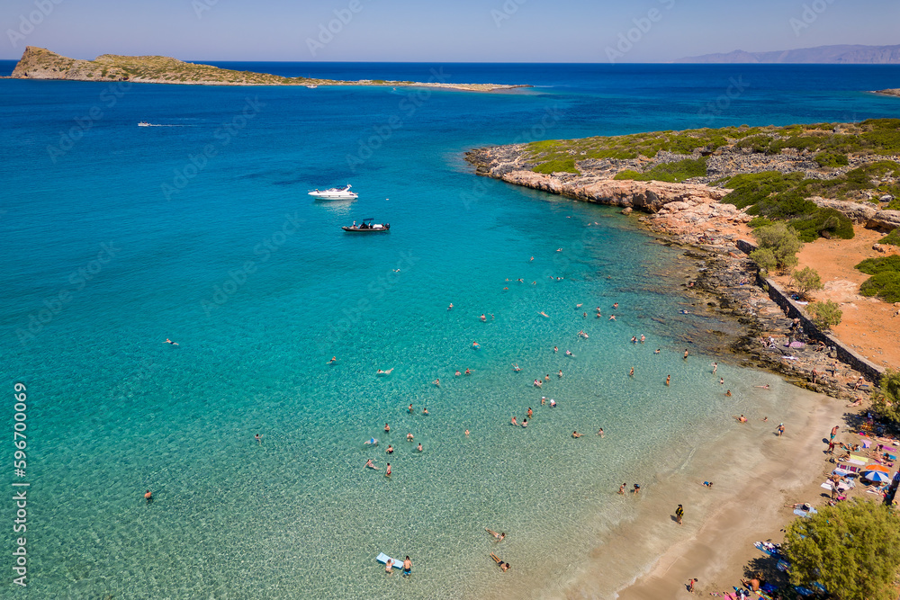 Aerial view of a small beach and crystal clear ocean with swimmers on a hot summers day in Crete (Kolokitha)