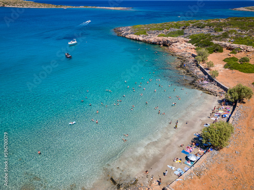 Fototapeta Naklejka Na Ścianę i Meble -  Top down aerial view of tourists on a small beach with crystal clear blue ocean on the island of Crete, Greece