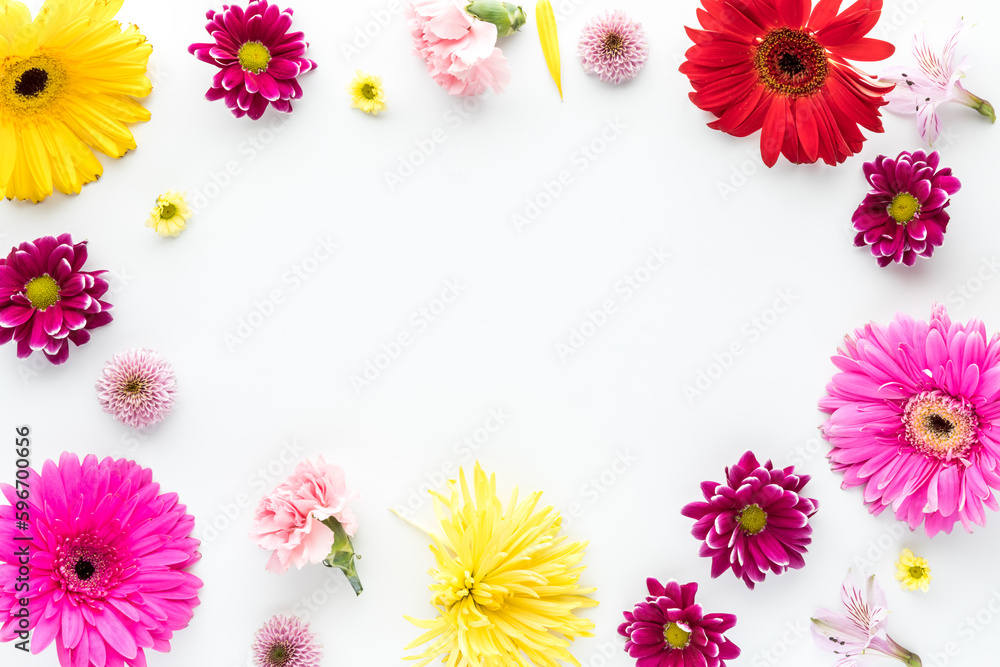 A border of assorted bright fresh flower blossoms with copy space in the middle.