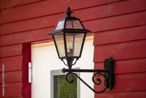 Exterior of red house with white window and lantern on the wall