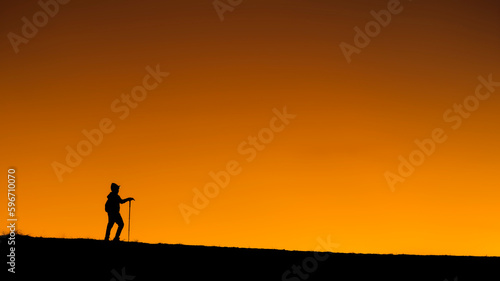 alone hiker hiking is silhouette walking on mountains, sunset. Ascending a mountain peak at sunset with the silhouette in the background. sport and adventure. Weekend activities. walks on mountains