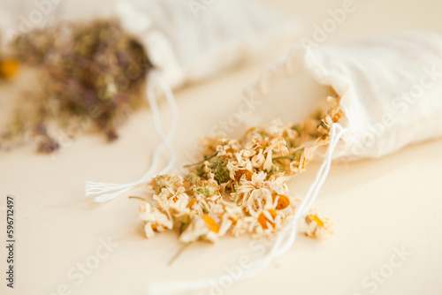 dried herbs at cotton white bags from above. Sachets filled with medicinal chamomilla and bunches