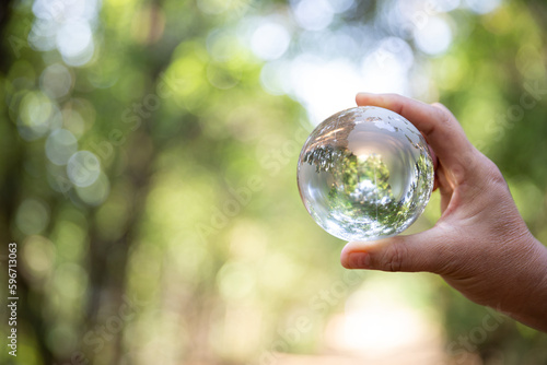 Earth crystal glass globe ball in human hand, environment day concept. Sustainable development of natural resources and the environment. Protecting the world's forest resources.