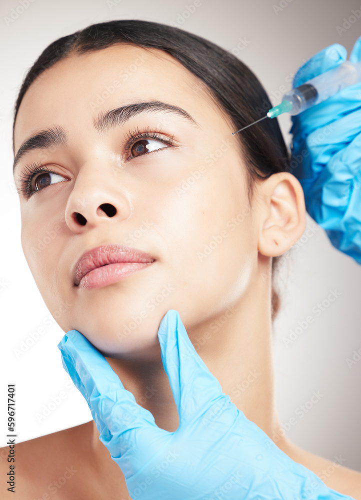 Portrait of a young mixed race woman getting botox against a grey studio background. Hispanic female taking care of her skin with a checkup against a background Portrait of a young mixed race woman getting botox against a grey studio background. Hispanic female taking care of her skin with a checkup against a background
