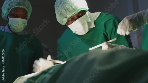 nurse handing a surgical instrument to the surgeon in operating room.