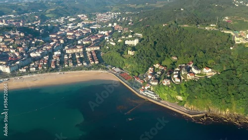 Panoramic view of beautiful city San Sebastian - Donostia. View of Ondarreta Beach. Igeldo Mountain , with beautiful urbanisation.  Igeldoko Dorrea tower in the left corner Drone tracking right photo