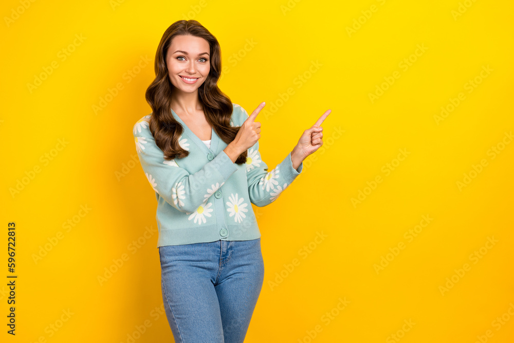 Photo of adorable pretty woman wear turquoise cardigan pointing two fingers empty space isolated yellow color background Photo of adorable pretty woman wear turquoise cardigan pointing two fingers empty space isolated yellow color background